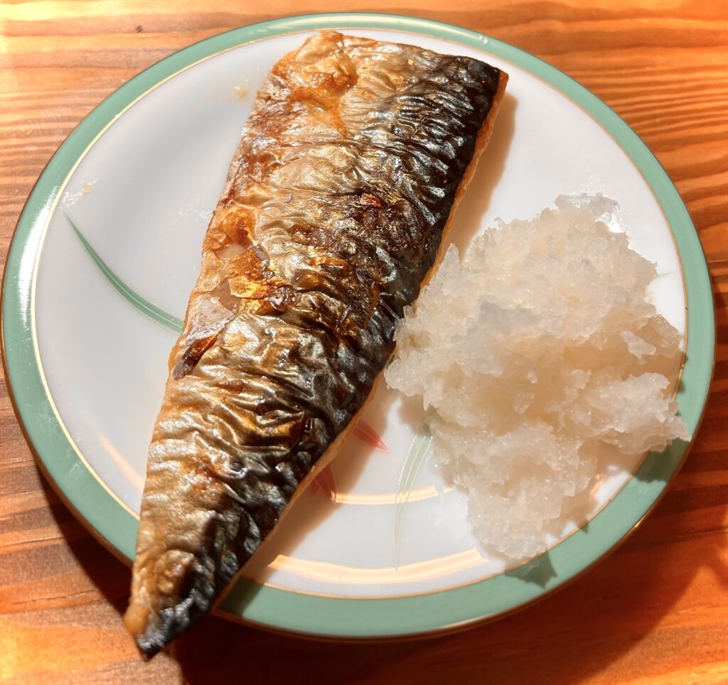 香ばしく焼き上げた塩サバとたっぷりの大根おろしを盛り付けた皿のアップ写真。」