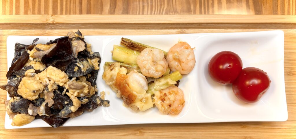 キクラゲと卵の炒め物、エビと長ネギの炒め物、ミニトマトを盛り付けた長方形の白い皿の副菜プレート。