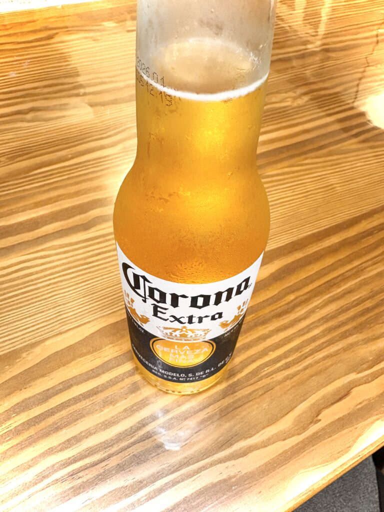 冷えたコロナ・エキストラの瓶ビール。木目のテーブルに置かれている