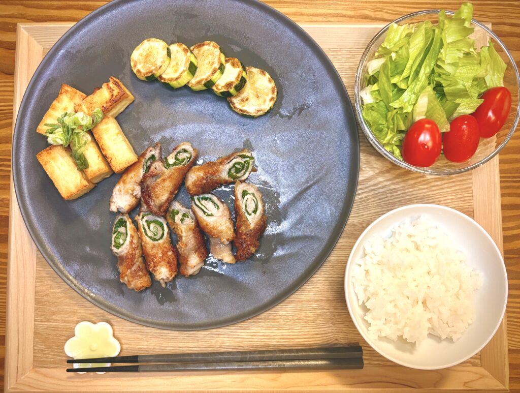 豚肉の大葉巻きソテー、焼き豆腐のねぎ添え、ズッキーニのソテー、フレッシュサラダ(レタスとミニトマト)、白ごはんを木のトレイに盛り付けた和風献立