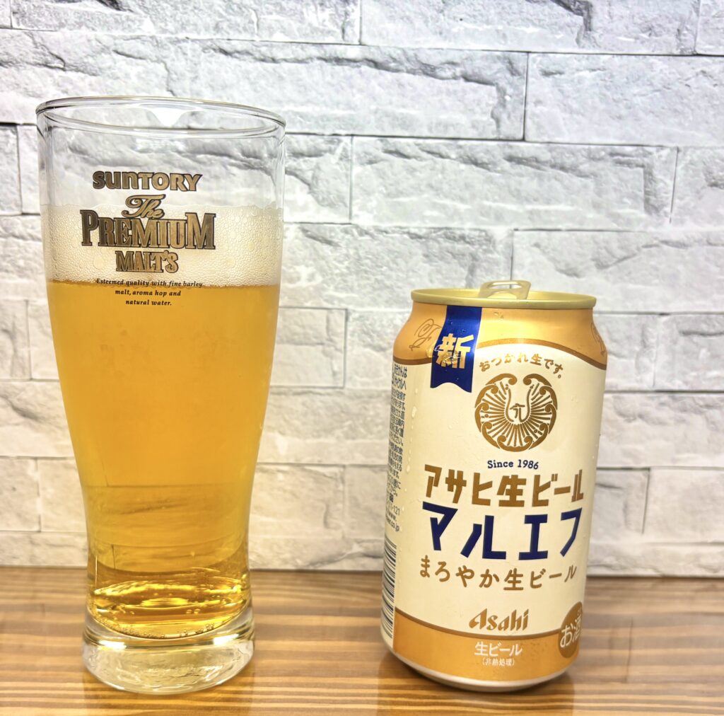 アサヒ生ビール〈マルエフ〉の缶。白と金を基調にしたレトロ感のあるデザインで、「おつかれ生です。」の文字が入っている。木目調のテーブルに置かれている。