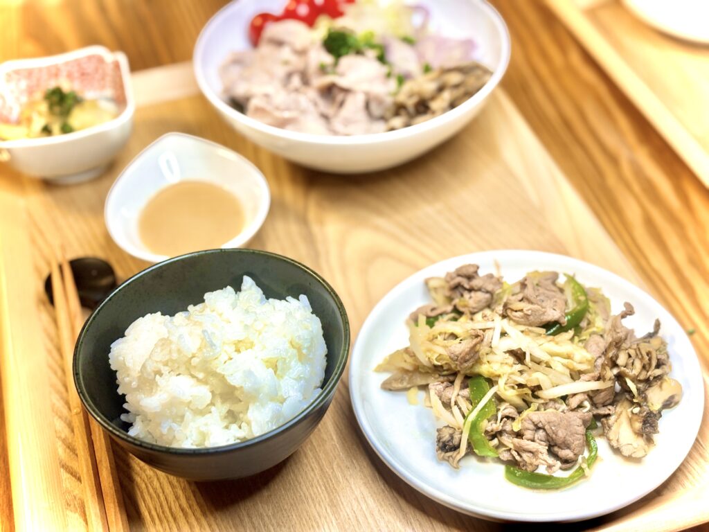 「白ごはん、牛肉と野菜のジンギスカン炒め、冷しゃぶサラダ、小鉢とゴマだれが並んだ和風定食」