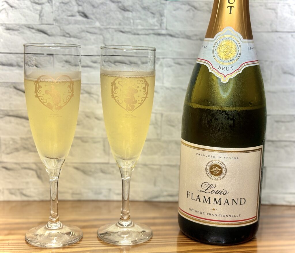 フランス産スパークリングワイン『Louis Flammmand Brut』のボトルと、泡立ちの美しいグラス2杯を並べた乾杯シーン。おうちでレストラン気分を楽しむ特別な一枚