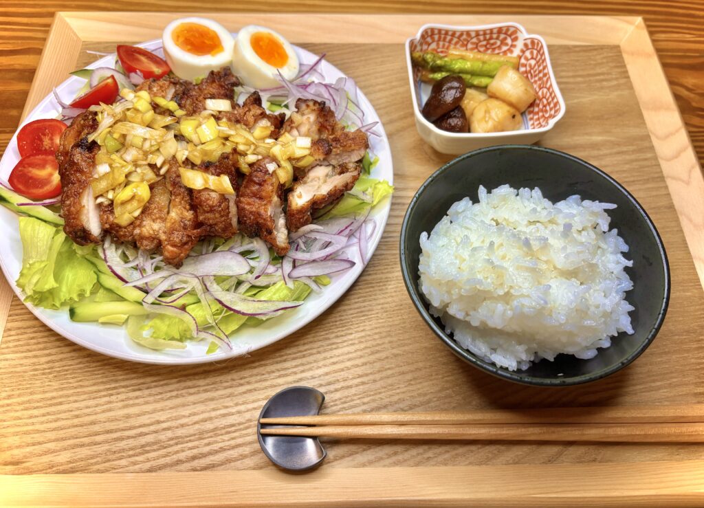 香味ダレをかけた油淋鶏、半熟卵、野菜を盛り合わせたワンプレートと白ごはん、副菜のホタテとアスパラ炒め