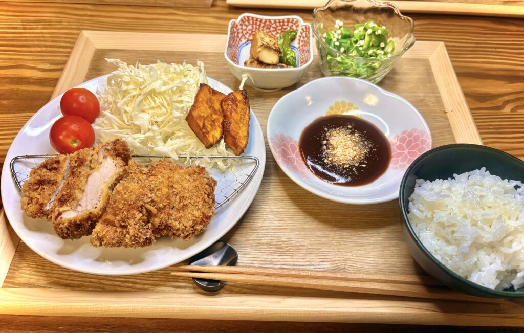 ヒレカツ、キャベツ、かぼちゃの素揚げ、副菜、ごはんを並べたバランスの良い和定食