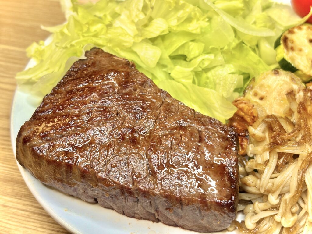 厚切りに焼き上げたジューシーなステーキ。照りのある表面が食欲をそそり、横にはシャキシャキのレタスやズッキーニ、きのこが添えられている