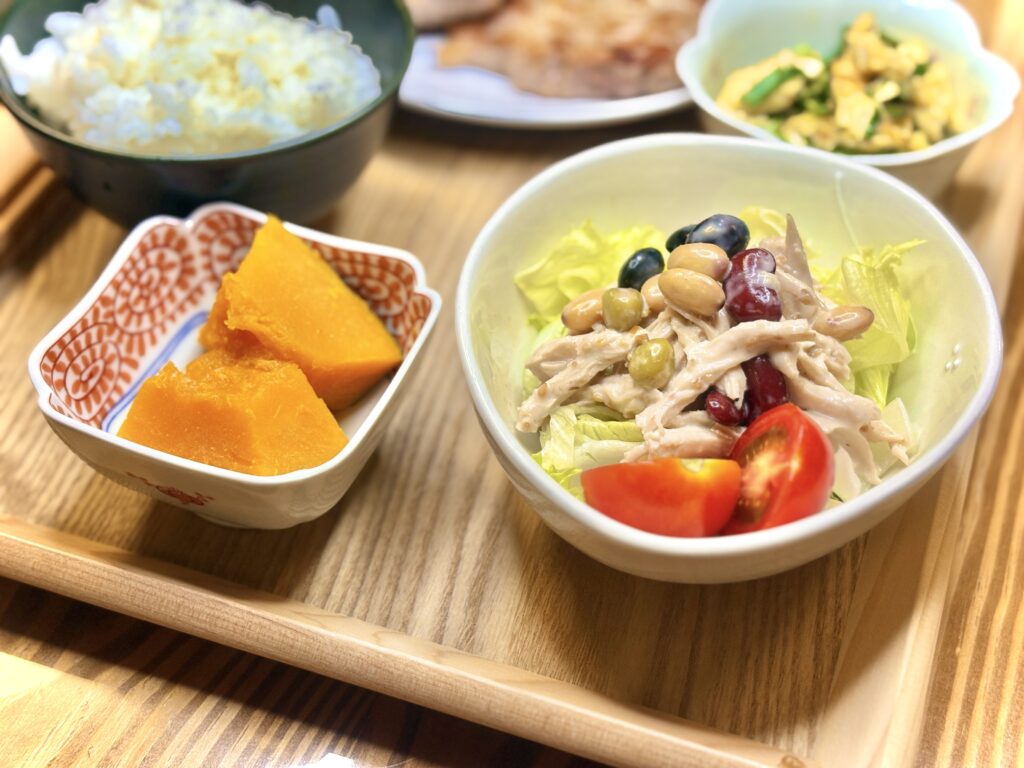 彩り豊かな豆と鶏ささみのサラダ、甘く煮含めたかぼちゃの煮物、白ごはんと副菜が並ぶ和食の晩ごはん