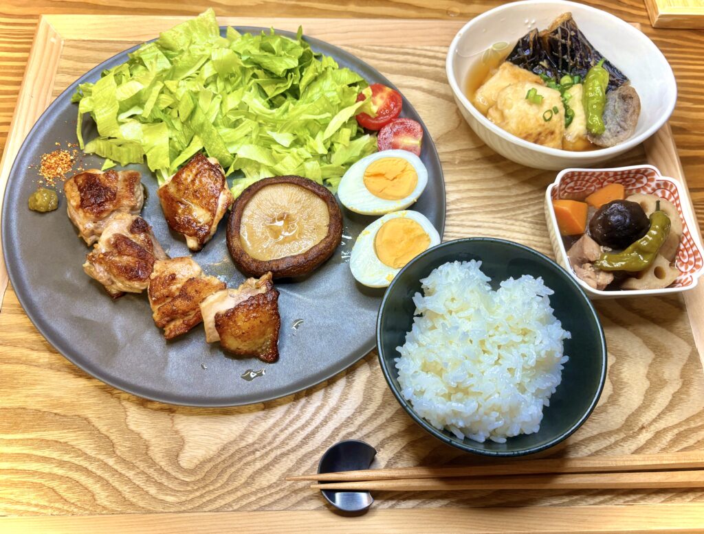 名古屋コーチンの塩焼き、椎茸ステーキ、半熟卵、たっぷりレタスを盛りつけたプレート。筑前煮、ご飯、揚げ出し豆腐も添えられた和食定食
