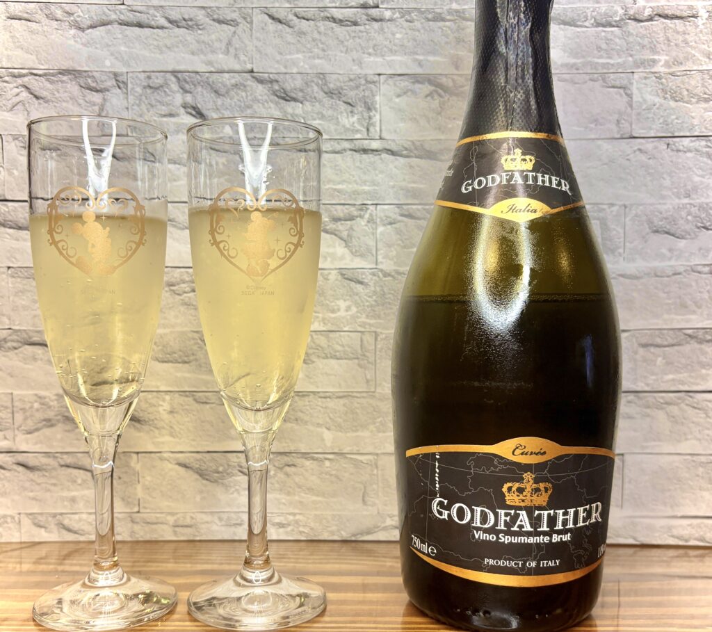 イタリア産スパークリングワイン『GODFATHER』のボトルと、注がれたグラス2つ。乾杯のシーンにぴったり」