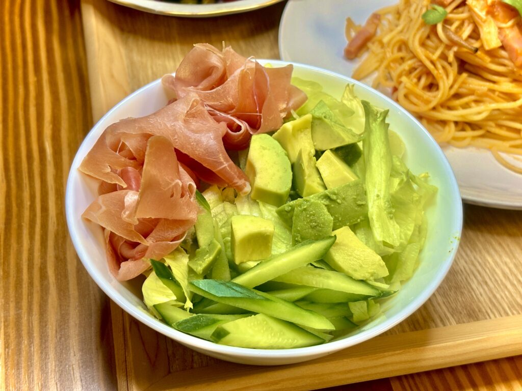 「旦那キッチンの生ハムとアボカドのサラダ。レタスときゅうりを合わせた彩りサラダで、濃厚なアボカドと塩気のある生ハムが相性抜群。おうちレストラン風の一品。」