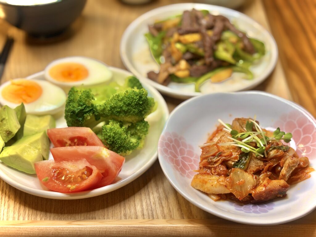 旦那キッチンの晩ごはん。ツヤツヤの豚キムチに、ブロッコリー・トマト・アボカド・ゆで卵の彩り副菜プレートを添えたおうちごはん。バランスのとれた中華風献立。
