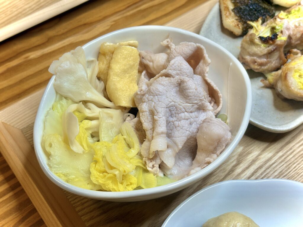 白い器に盛られた冷しゃぶサラダ。湯通しされた豚バラ肉と、白菜・まいたけ・厚揚げが彩りよく並ぶ。シンプルながら優しい湯気と温かみが伝わる、家庭的でほっとする一品。