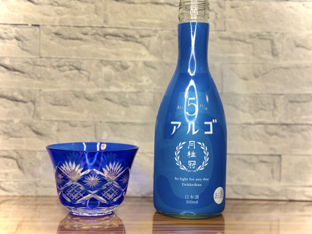 月桂冠『アルゴ』の青いボトルと、カットが美しい青色の切子グラス。爽やかな色合いが印象的な日本酒のワンショット。