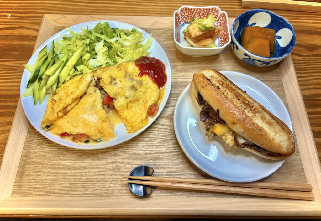 フィリーズチーズステーキサンドとトマトバジルオムレツの洋風ディナー。厚揚げのねぎごま油炒めとかぼちゃ煮を添えた旦那キッチン流おうちレストラン風の食卓。