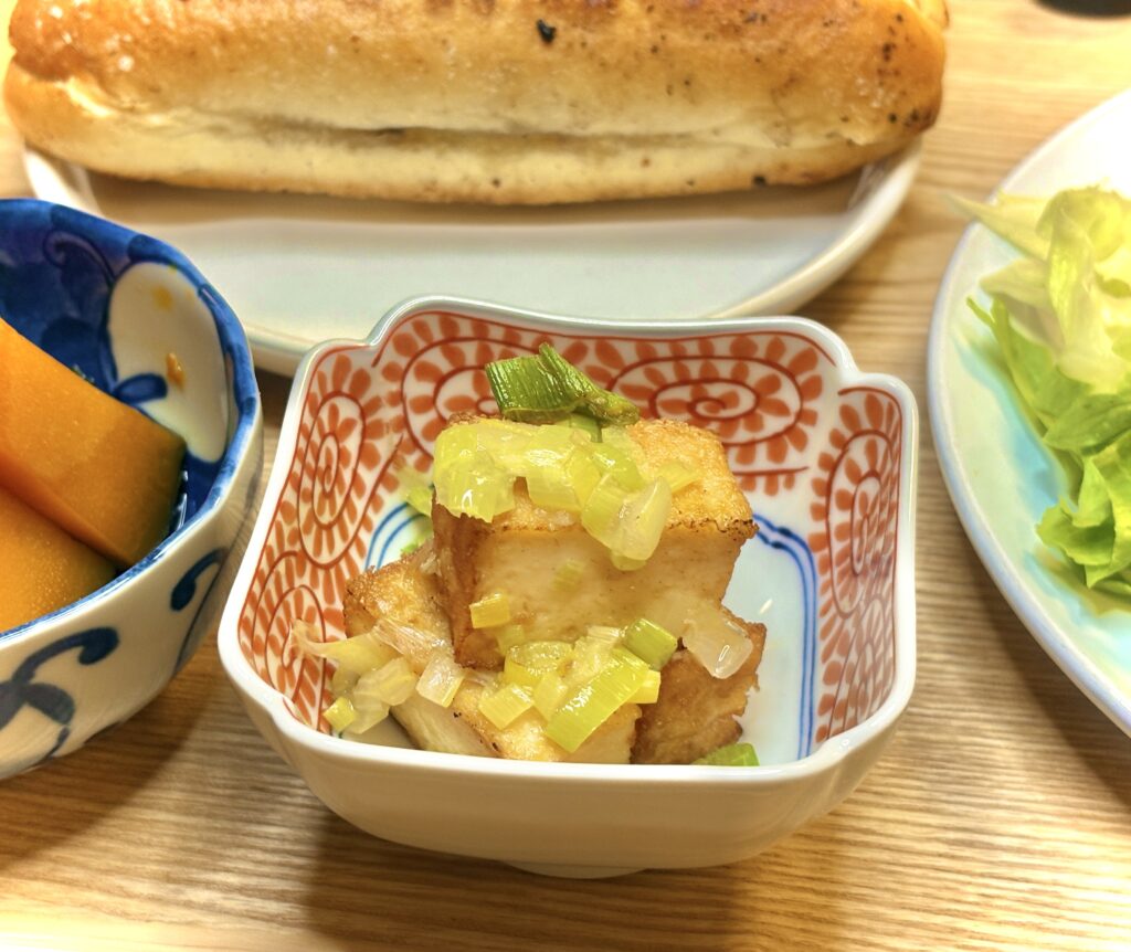 厚揚げに香ばしいねぎごま油をかけた副菜。カリッと焼かれた厚揚げに、ねぎの香りが食欲をそそる一品。