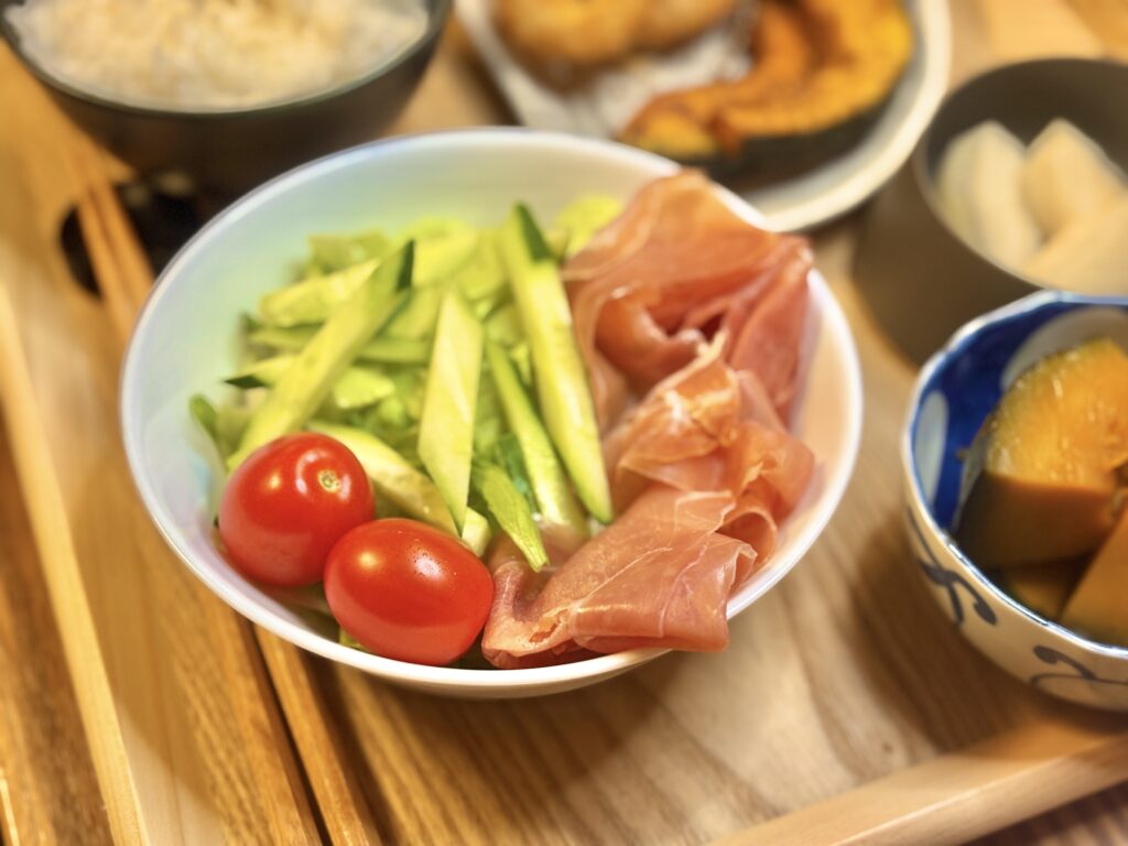 生ハム、レタス、きゅうり、ミニトマトを盛り合わせたサラダ。彩りが美しく、シンプルながらも食卓を華やかにする一皿。