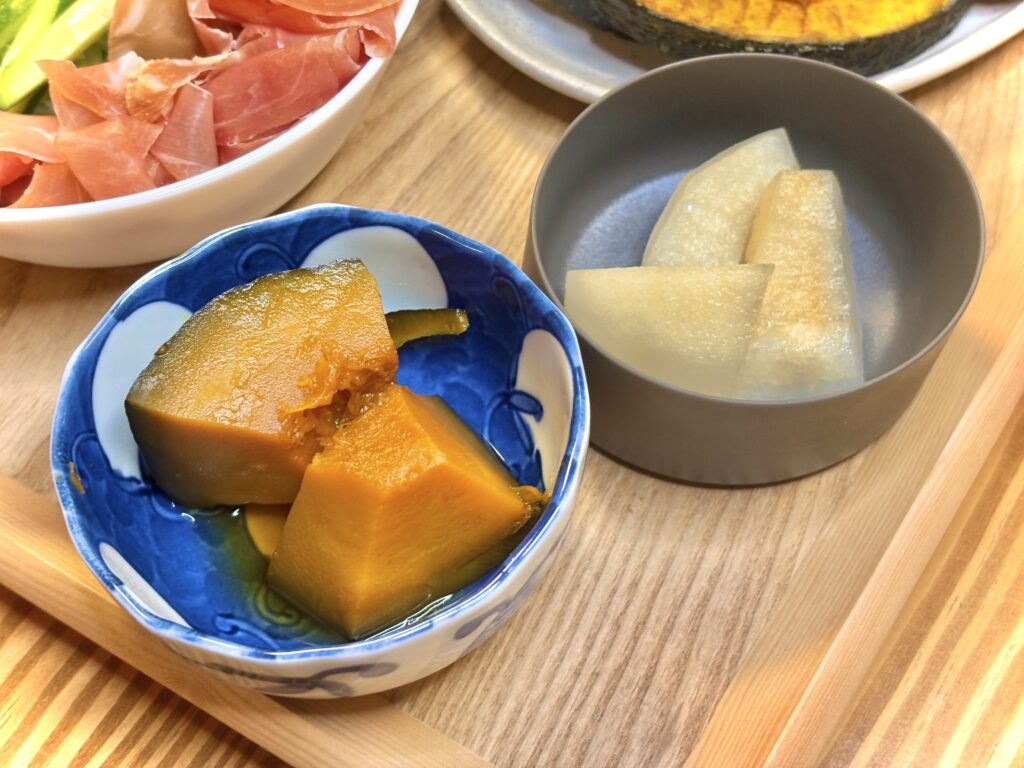 かぼちゃの煮物とデザートの梨を並べた小鉢。やさしい甘みの煮物とみずみずしい果物が食卓を締めくくる、ほっとする一皿。