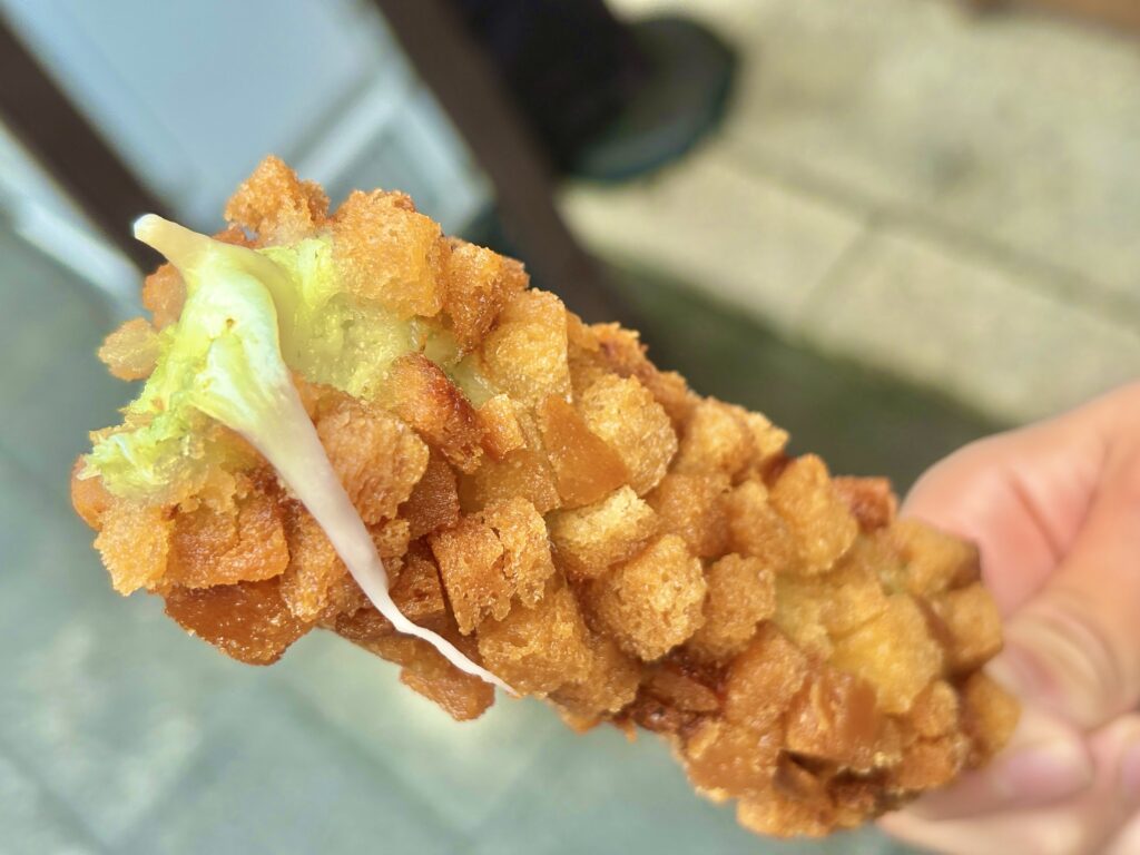 伊勢おかげ横丁の人気食べ歩きグルメ、ハッシュドポテトチーズドッグ。カリカリのポテト衣の中から、とろ~りチーズが伸びる!見た目も楽しく、揚げたての香ばしさがたまらない一本。