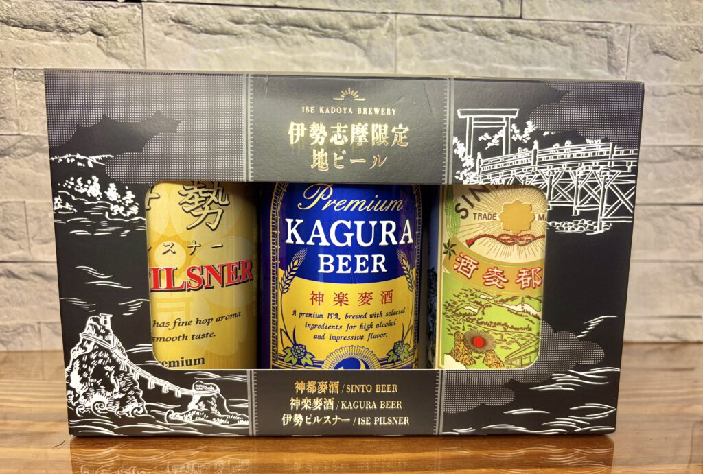 伊勢志摩限定クラフトビール3本セットのパッケージ写真。
「伊勢ピルスナー」「神楽麦酒(KAGURA BEER)」「神都麦酒(SINTO BEER)」が並び、
黒地に白のイラストで伊勢の風景(夫婦岩や鳥居の橋)が描かれた高級感あるデザイン。