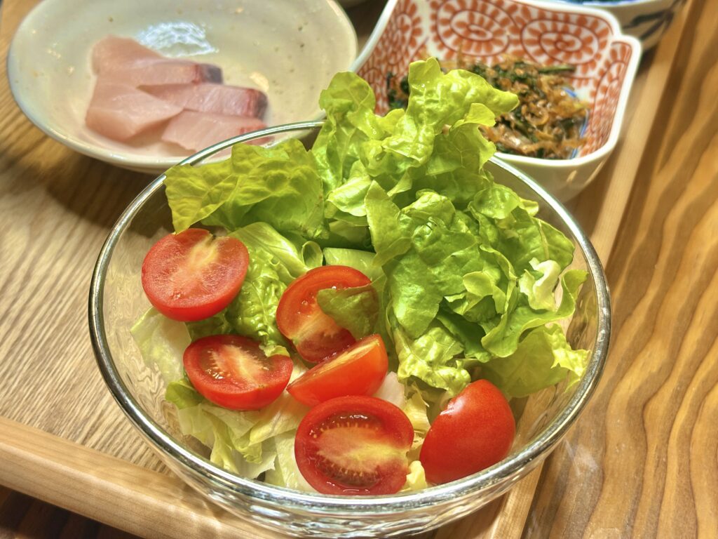 グリーンリーフとプチトマトを盛り合わせたフレッシュサラダ。透明なガラスボウルに彩りよく盛られ、食卓に爽やかさを添える一品。