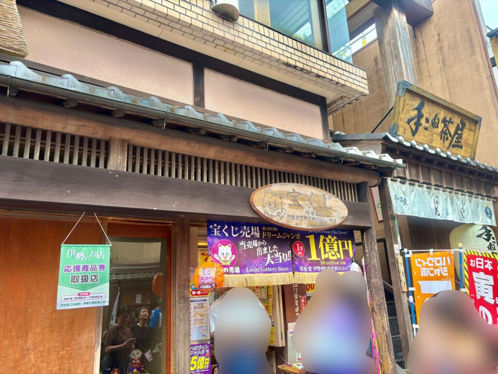 おかげ横丁にある宝くじ売り場の外観。木の看板と「1億円当選!」ののぼりが目を引くレトロな雰囲気の店舗で、観光客が立ち寄っている様子。