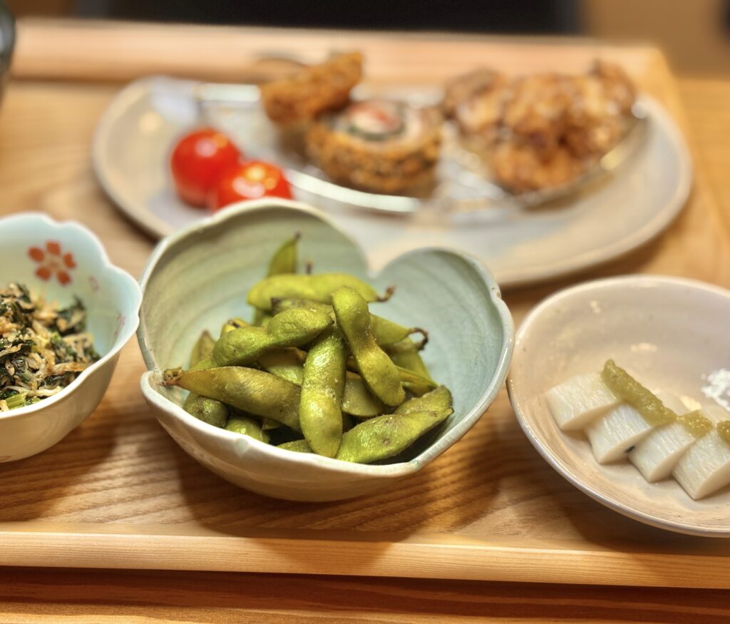 丹波黒枝豆とわさびを添えたかまぼこ、小鉢が並ぶ食卓。木の温もりを感じる器に盛りつけられている
