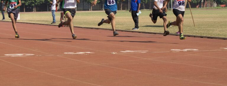 陸上トラックでリレーの選手たちがゴールを目指して全力で走る様子。運動会のクライマックスを感じさせるシーン。