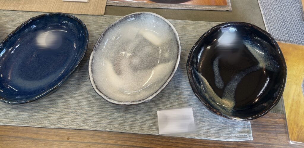 丹波焼の陶器皿3枚。左から青、白、黒の落ち着いた色合いの器が並んで展示されている。