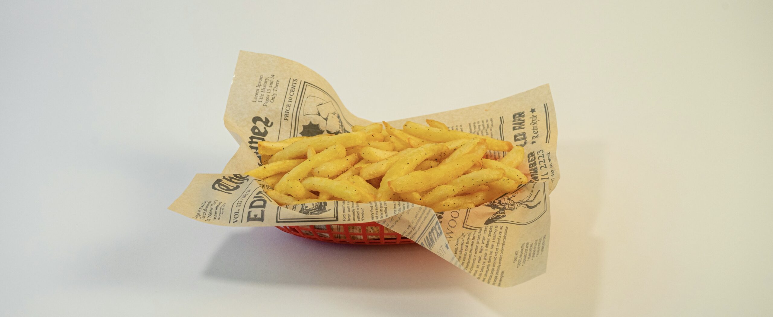 紙に包まれたフライドポテト。カリッと揚がったポテトがバスケットに盛り付けられ、香ばしさが伝わる