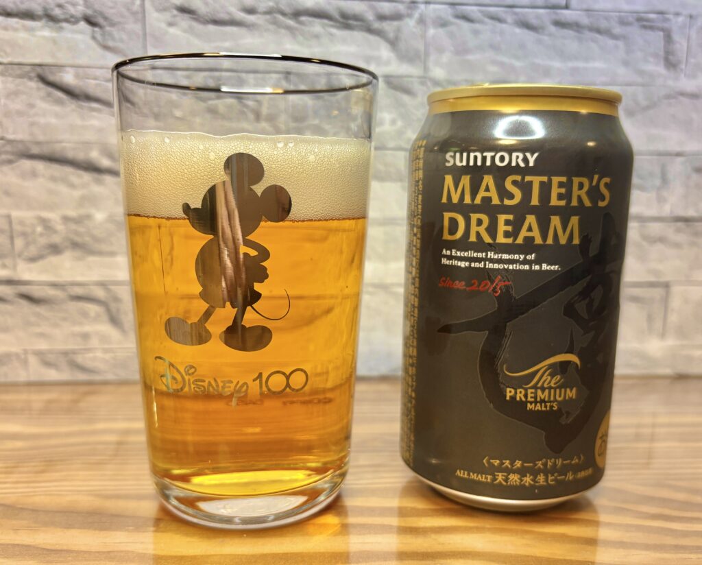 ミッキーがプリントされたグラスに注がれたビールと、サントリーマスターズドリーム」の缶が並んでいる。透明感のある黄金色のビールと細やかな泡が美しく、晩酌の楽しさが伝わる写真。