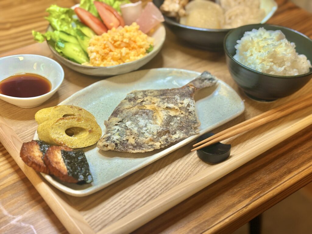 カレイの唐揚げを中心に、卵サラダや生野菜、副菜、ごはんを並べた和食の晩ごはん