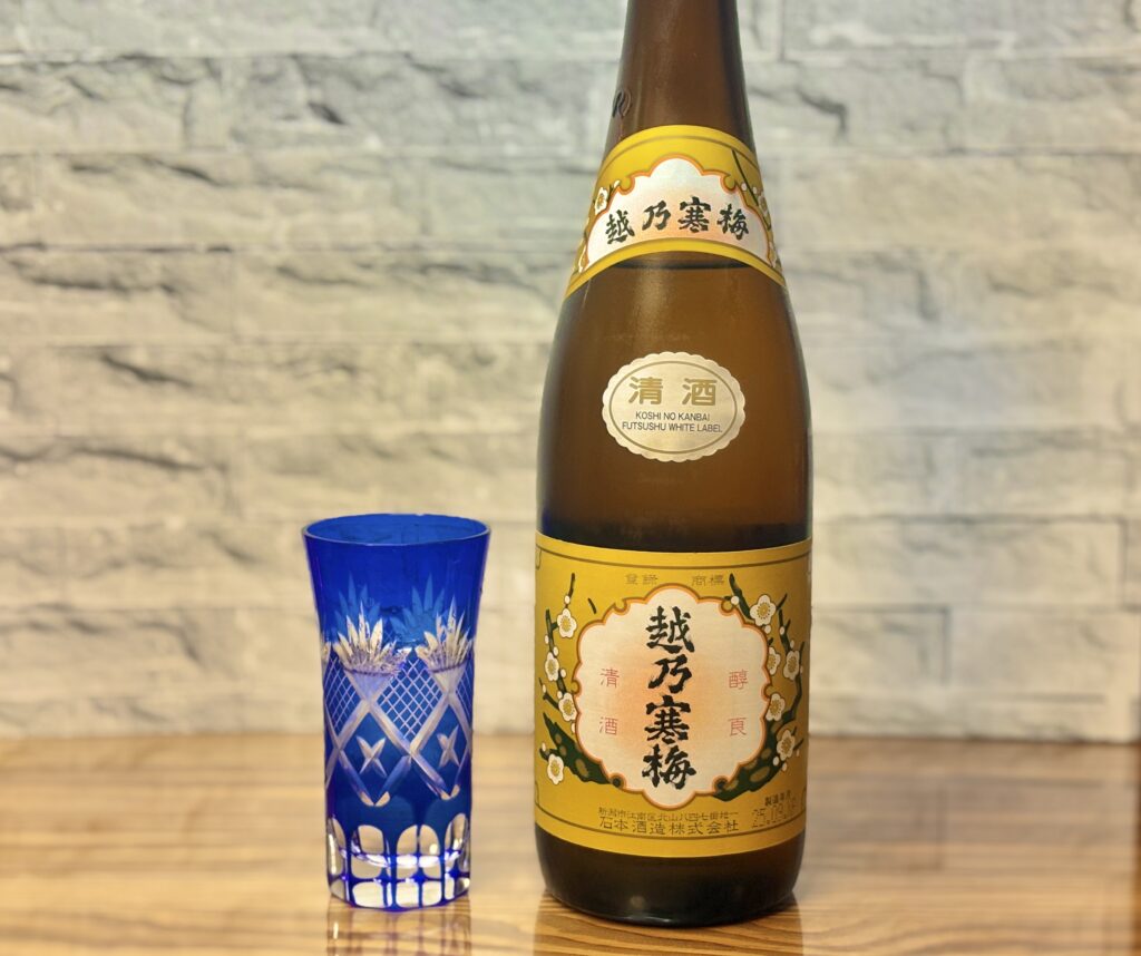 越乃寒梅の瓶と青い切子グラスを並べた日本酒の写真