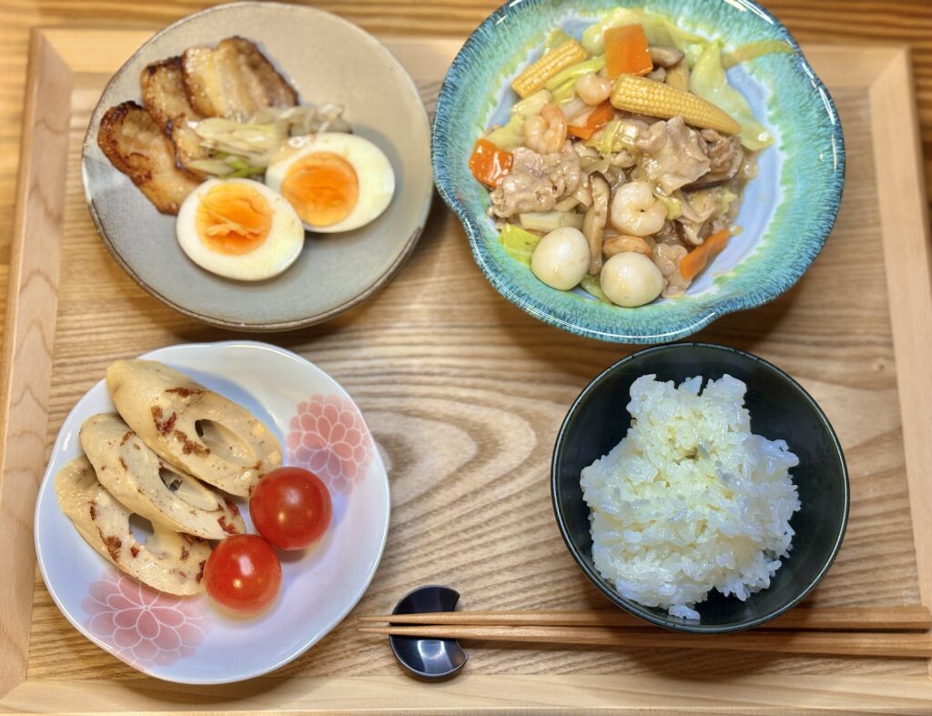 八宝菜、ネギチャーシュー煮卵、豆腐ちくわとミニトマト、白ごはんが木のトレイに並んだ食卓の写真
