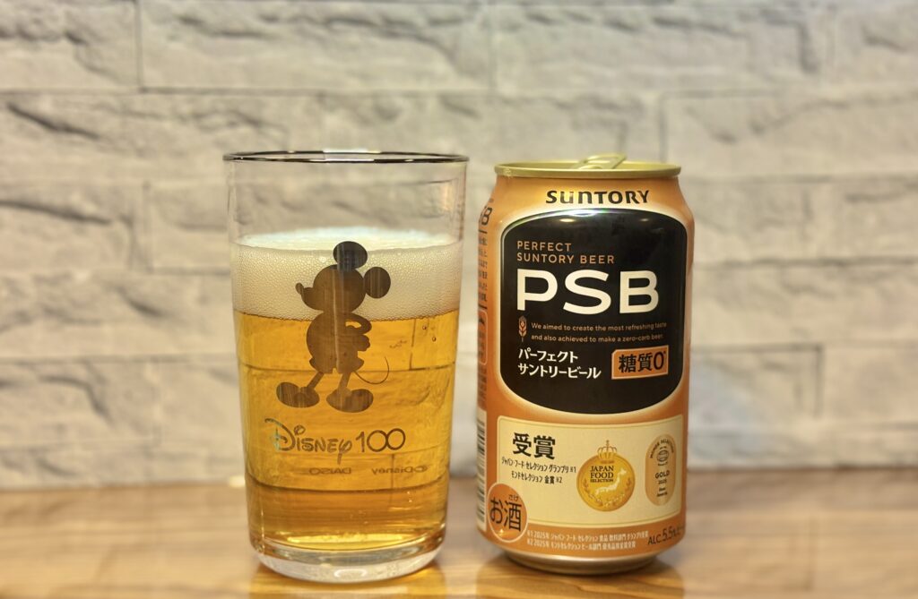 ミッキーのグラスに注がれたビールと、サントリーPSBの缶を並べて撮影した写真
