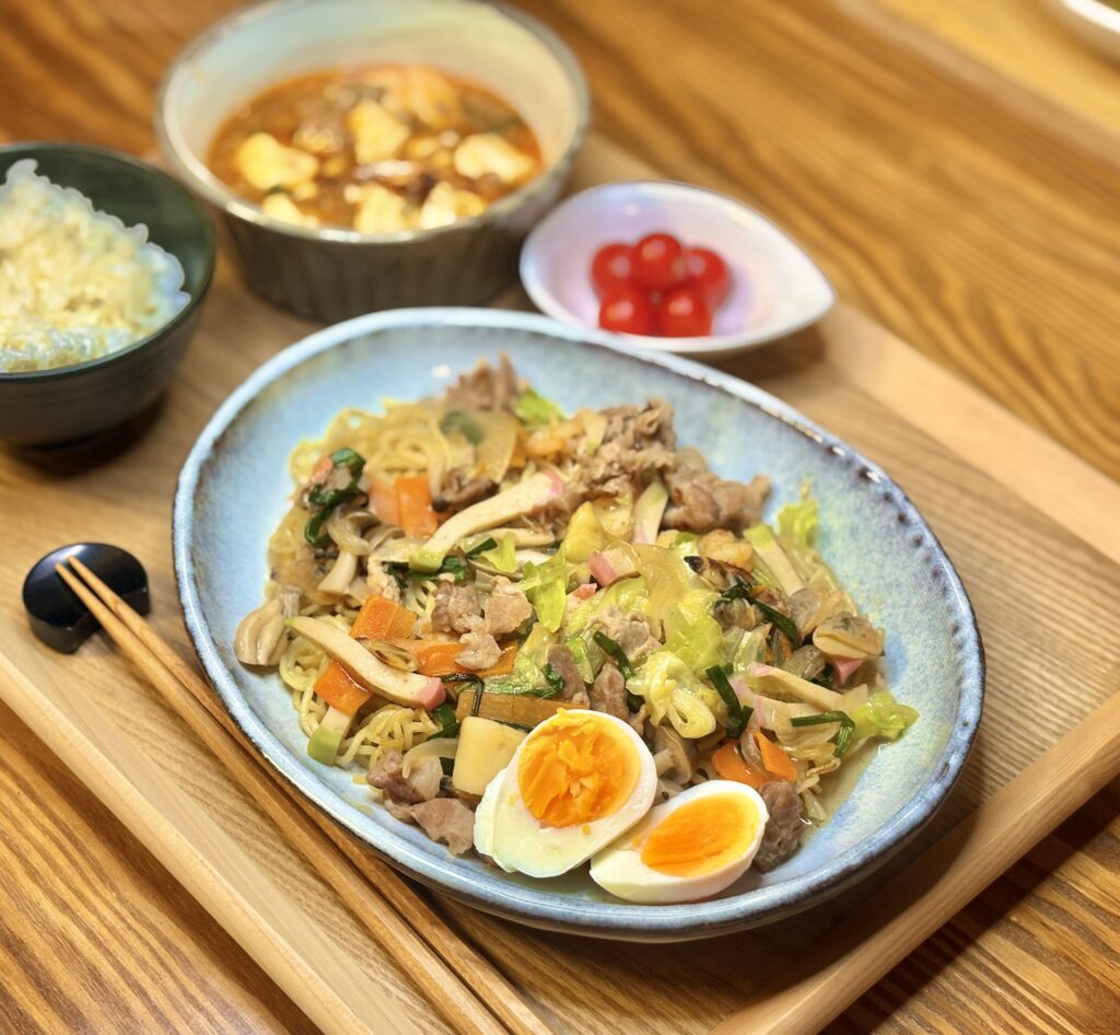 餡掛け焼きそばをメインに、奥に麻婆豆腐、白ごはん、ミニトマトが並んだ晩ごはんプレート。色とりどりの具材が使われた焼きそばが皿いっぱいに盛られ、食欲をそそる構図。