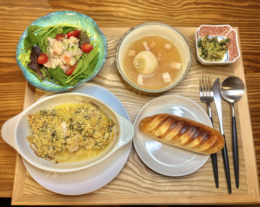鳥もも肉の香草パン粉焼き、かぶのスープ、ポテトサラダのベビーリーフサラダ、かぶの葉の胡麻炒め、パンを並べた洋食プレートの食卓。