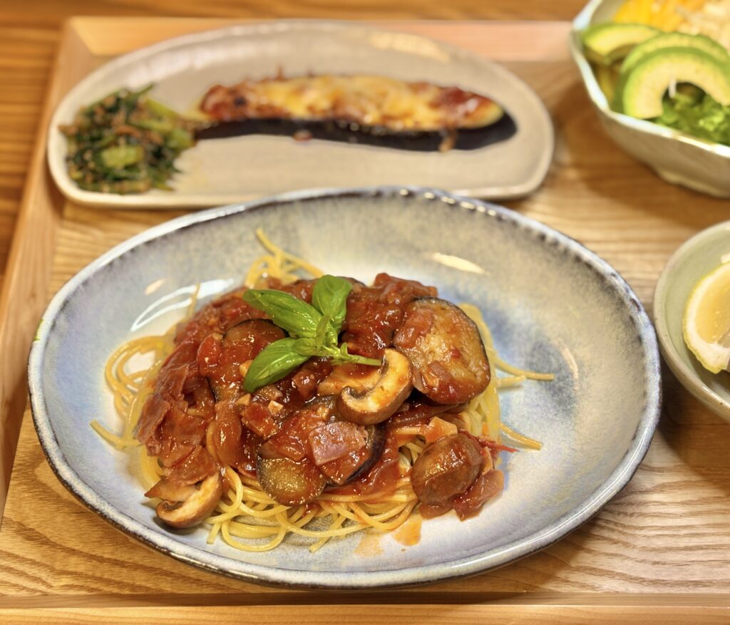 ・バジルをのせたナスときのこのトマトパスタのアップ写真
