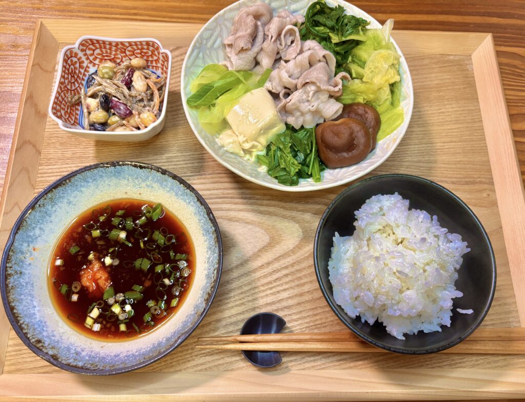 豚しゃぶと彩り野菜、小鉢の豆サラダ、ポン酢だれ、ごはんを木のトレイに並べた和食献立の写真