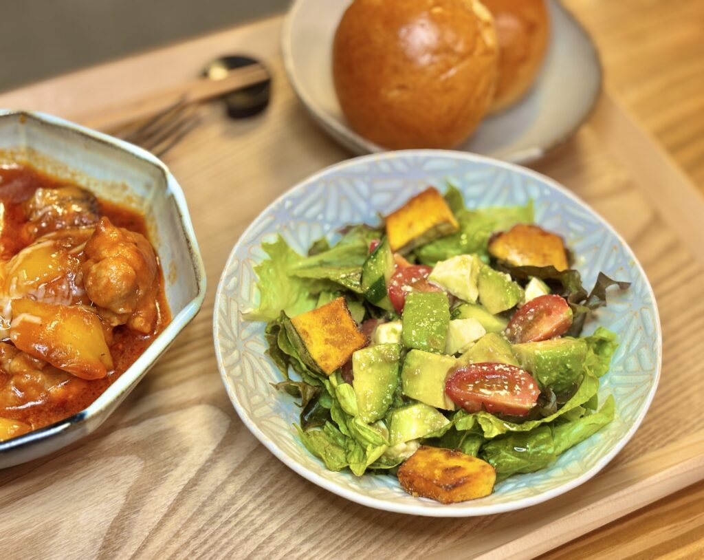 焼きかぼちゃ、アボカド、ミニトマトを合わせた彩りサラダ。レタスの上に具材がたっぷりの写真
