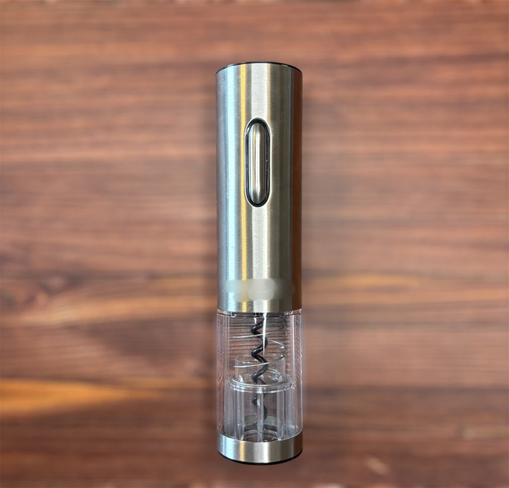 木目のテーブルの上に置かれたステンレス製の電動ワインオープナー。透明部分からスクリューが見えるスタイリッシュなデザイン。