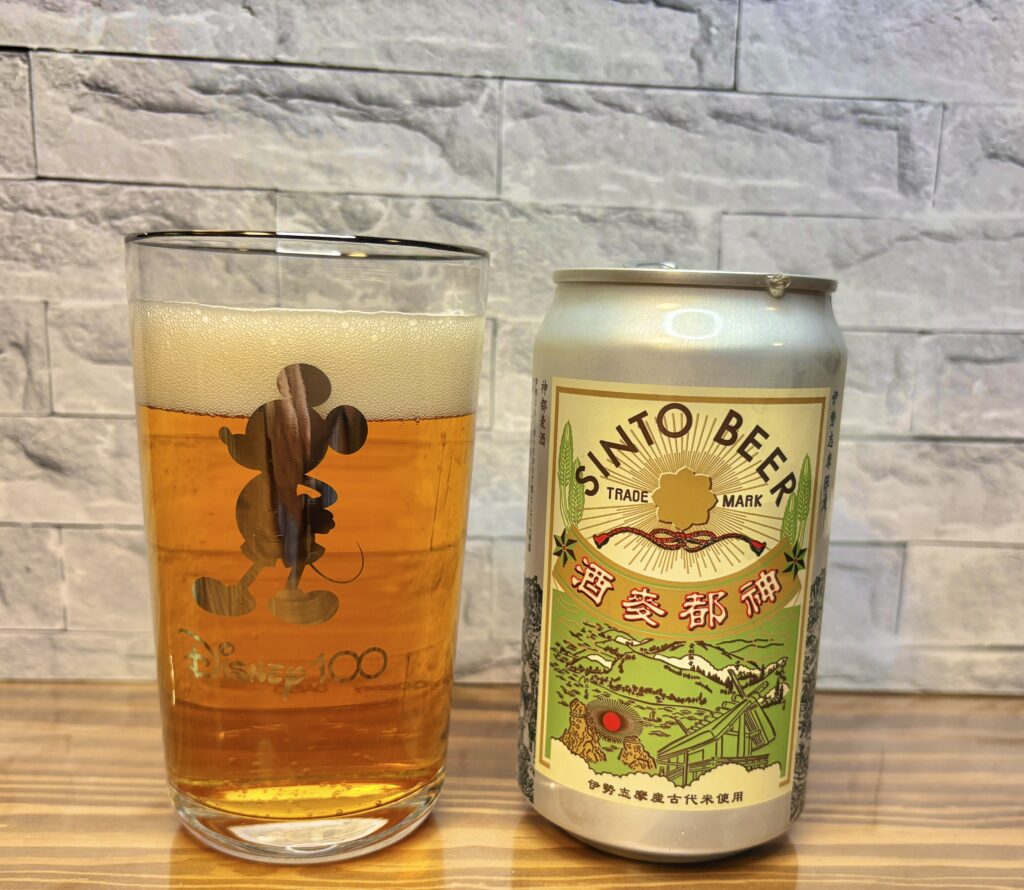 伊勢の地ビール『神都ビール』の缶と、ミッキーのイラスト入りグラスに注がれた琥珀色のビール。泡がきめ細かく立ち上がる、晩酌シーンの一枚