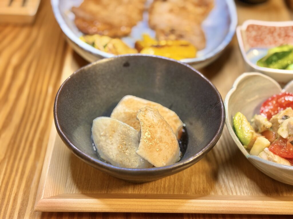 山芋とうふを器に盛り、醤油だれをかけた小鉢料理。なめらかな食感と優しい味わいが特徴。