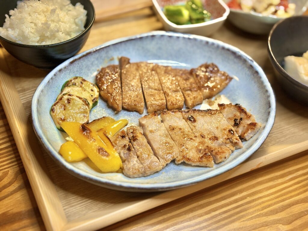 和豚もちぶたの生姜焼きと塩麹焼きを盛り合わせたメインディッシュ。付け合わせに焼きズッキーニとパプリカを添えた和風プレート。