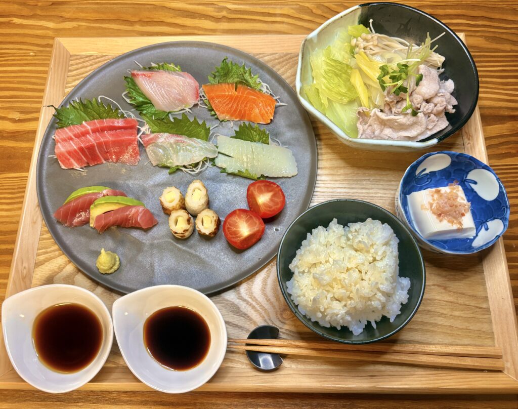 お刺身盛り合わせと豚しゃぶ、冷奴、ごはんが並ぶ彩り豊かな和食の夕食セット