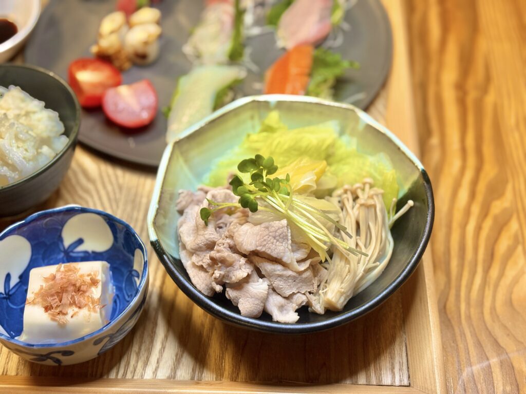 豚しゃぶとレタス、えのき、ねぎ、かいわれを彩りよく盛り付けた温野菜の和食鉢。冷奴とごはんを添えた栄養バランスの良い夕食セット