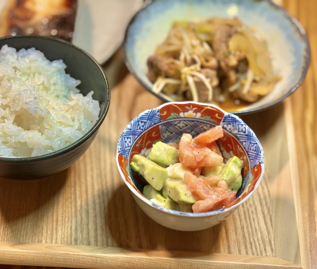 アボカドとチーズとトマトのサラダと、炊きたてごはんを並べた和食の食卓。