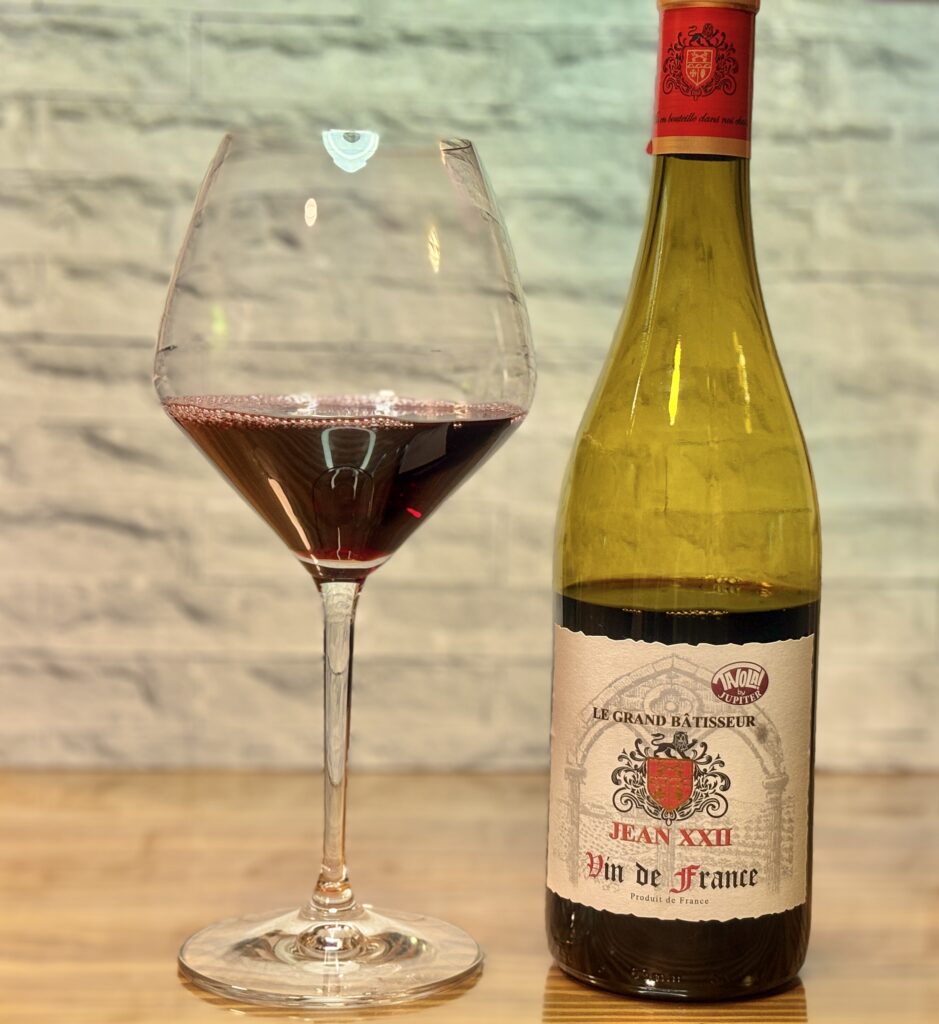 ジャン22世の赤ワインのボトルと、赤ワインが注がれた大きなワイングラスが並んでいる写真。