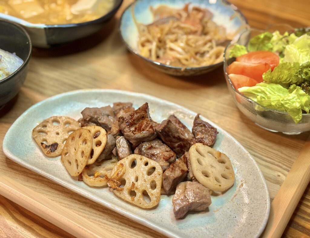 白い皿に盛り付けられたサイコロステーキとこんがり焼いたレンコンのスライス