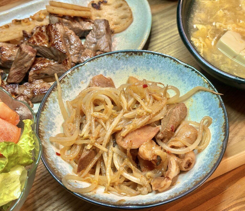 青い器に盛られた亀山ホルモンともやしの炒め物