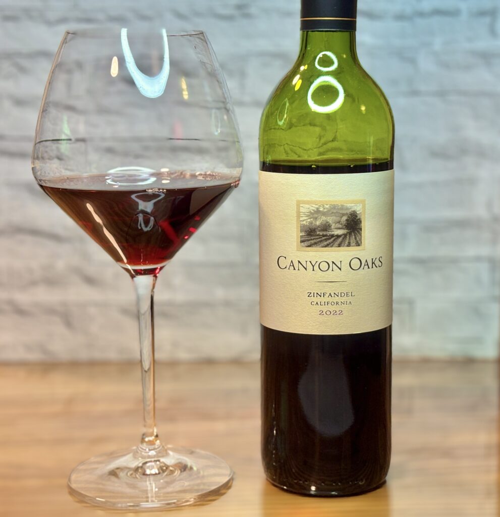 CANYON OAKSの赤ワインとワイングラスが並び、深い赤色のワインが注がれたグラスが印象的なテーブルショット。
